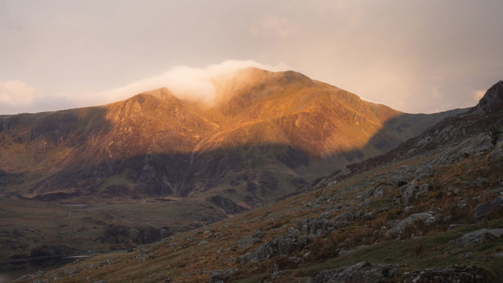 Trfyan mountain with soft golden light shining on the foggy mountain top as the sun rises. 