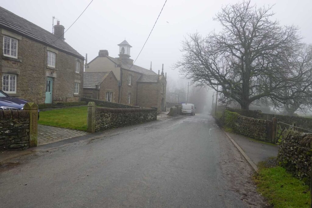 Quiet village road in Hollinsclough near Chrome Hill, with stone cottages and the Methodist church emerging through morning mist on one of the classic Chrome Hill walks